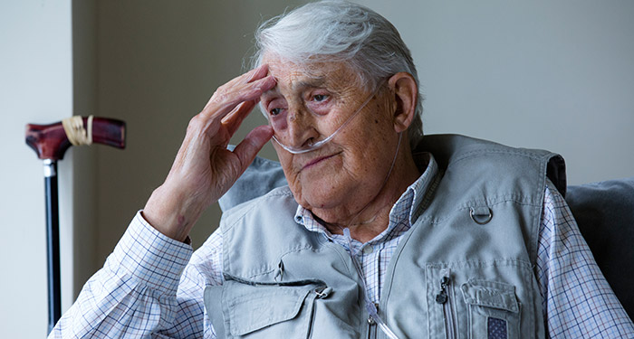 Sitzender, &auml;lterer Mann mit Nasenkan&uuml;le, der &uuml;ber seine Zukunft nachdenkt