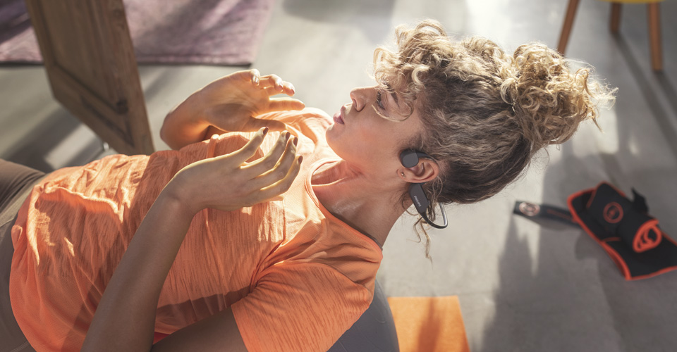 Athletin, die Open-Ear-Kopfh&ouml;rer beim Workout im Innenbereich tr&auml;gt