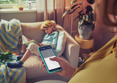 Elternteil, das die Philips Kopfh&ouml;rer f&uuml;r Kinder seines Kindes &uuml;ber das Smartphone kontrolliert